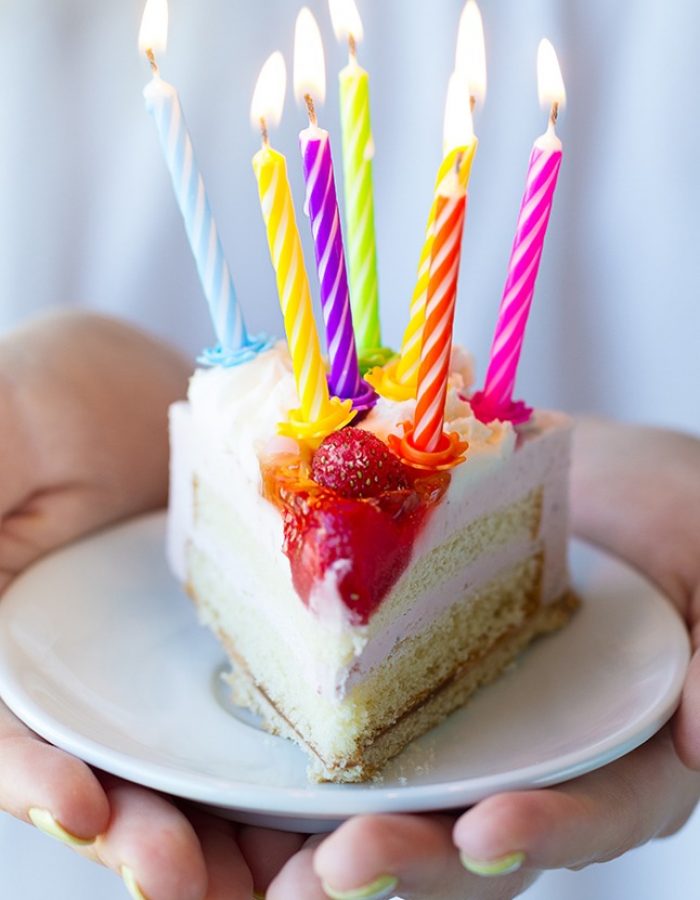 Girl holding beautiful appetizing birthday cake with many candle